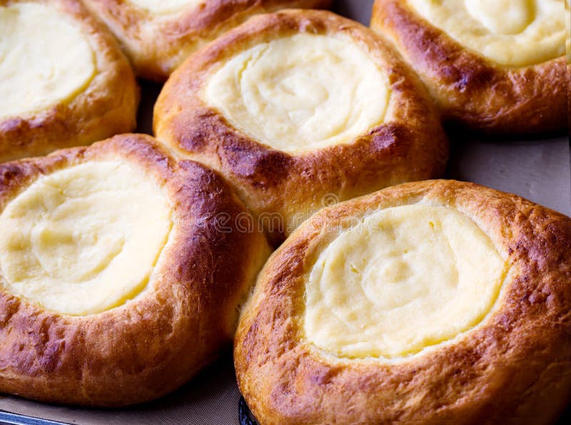 Open buns with cottage cheese vatrushka lying on a tray after baking. Сlose up